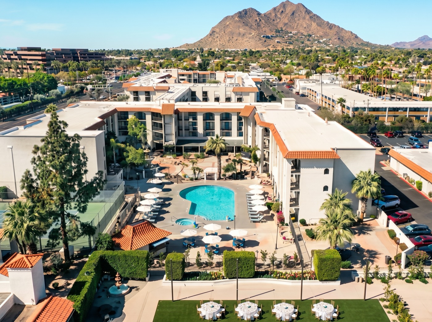 Aerial view of the Embassy Suites by Hilton Scottsdale Resort with white foam roofs below Camelback Mountain