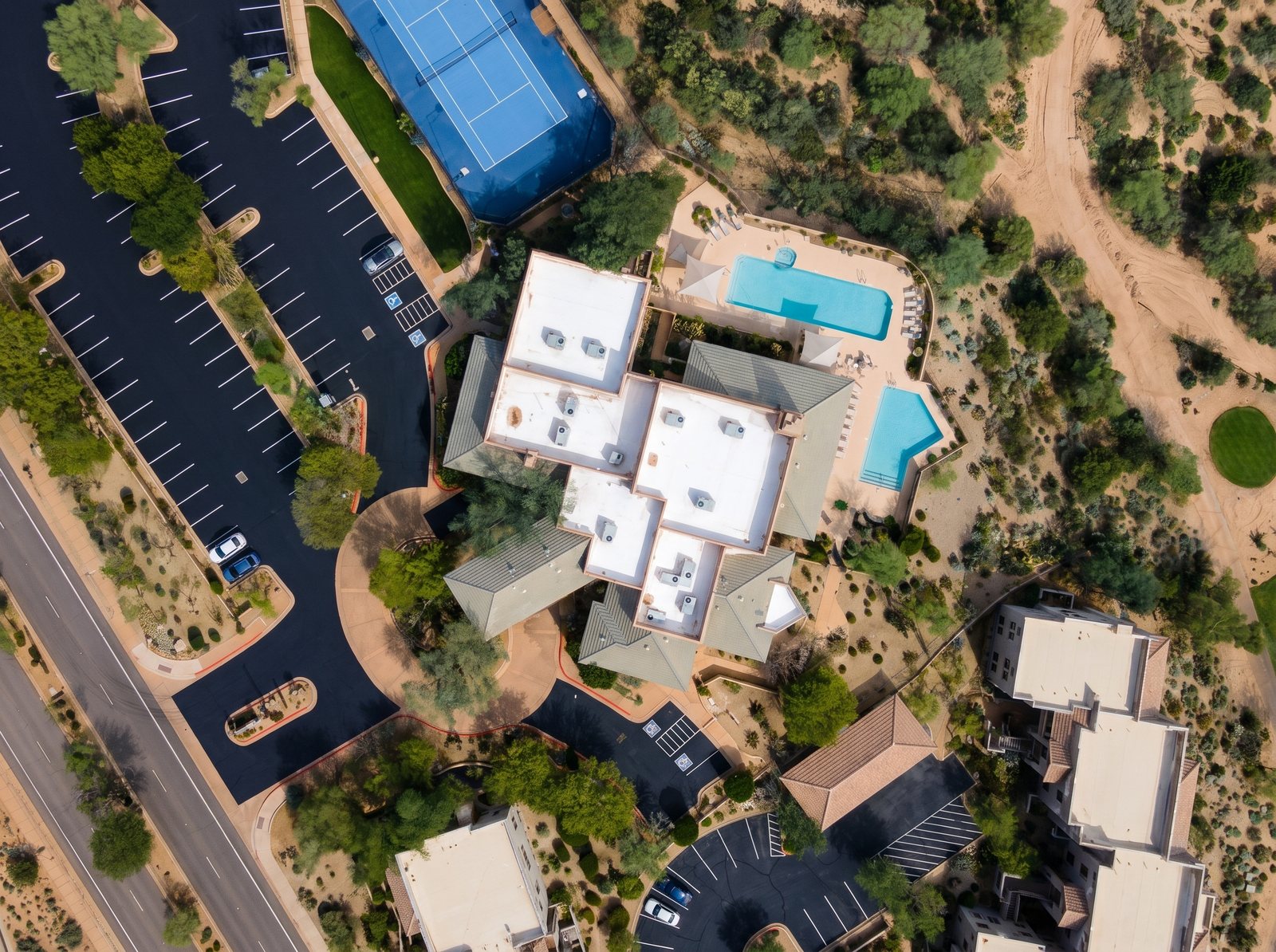 Top-down aerial of the Legend Trail Community Center in North Scottsdale showing the white spray foam roofs CDL Roofing installed, with tennis courts, pools, and desert landscaping